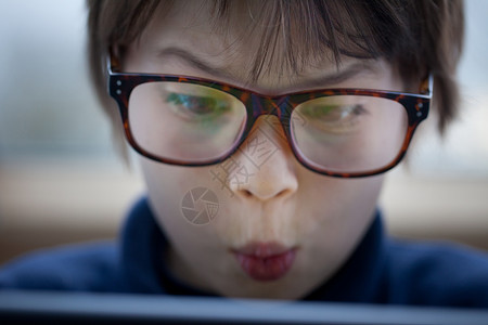 男孩用数码平板电脑拉脸的特写镜头图片