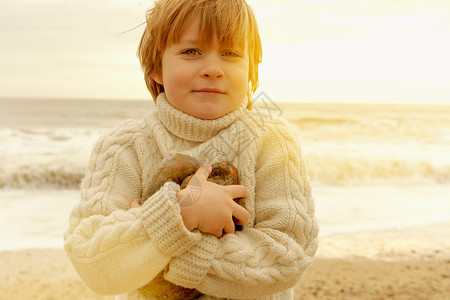 在海滩上拿着石头的小男孩图片