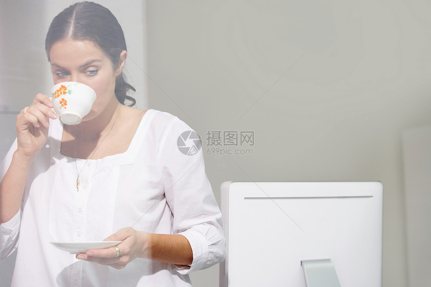 女人在电脑桌上喝茶图片