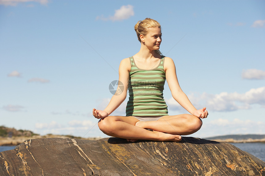 在岩石上做瑜伽的年轻女子图片