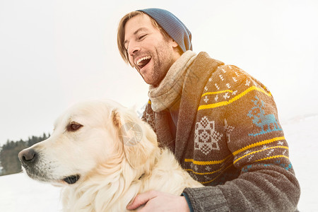 穿针织羊毛衫的男子在雪地狗背景图片