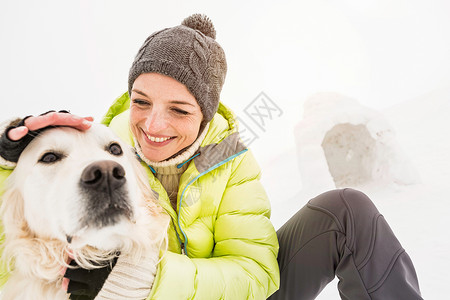 拍雪戴针织帽的女人拍狗的头背景