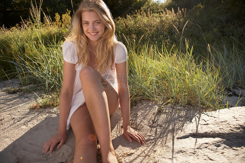 坐在海滩边的年轻女子图片