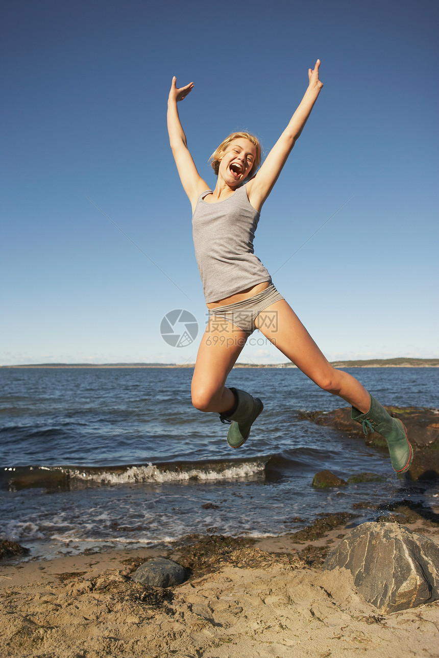 海滩边跳跃的女子图片