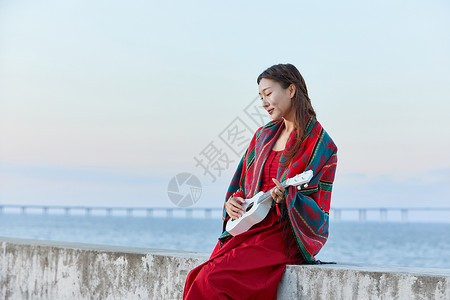 海边弹琴文艺女生海边谈尤克里里背景