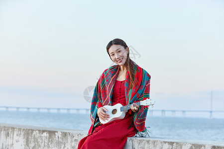 海边弹琴文艺女生海边谈尤克里里背景