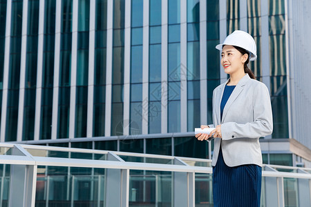 女性建筑工程师户外拿图纸背景图片