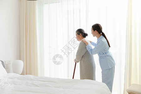 护工扶着拄着拐杖的老奶奶背景图片