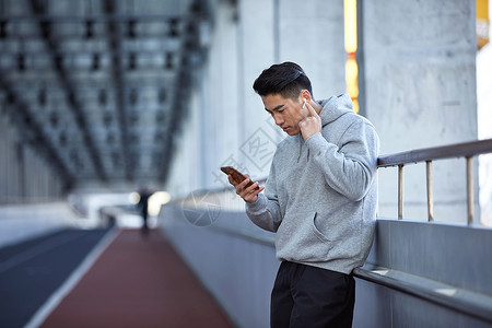 天桥玩手机年轻运动男士户外使用蓝牙耳机通电话背景