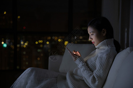 夜晚冬天冬季青年女性夜晚玩手机背景