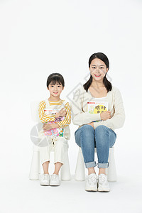 妈妈陪伴女儿坐在椅子上看童话故事书背景