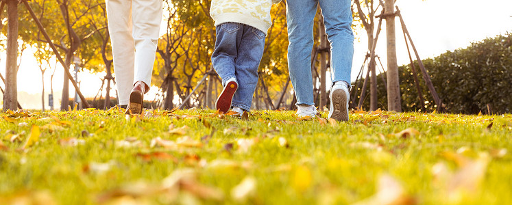 一家爸爸妈妈带着女儿在公园草地奔跑背景