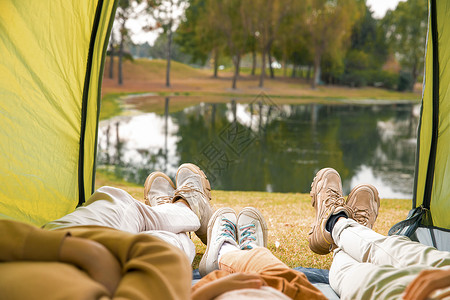 在公园休息一家三口躺在帐篷里欣赏风景背景