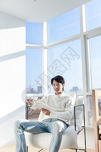 居家男性坐在阳台上看书图片