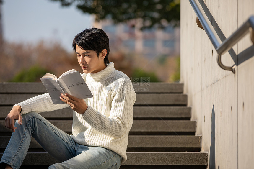 坐在楼梯上看书的青年男性图片