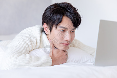 青年男性趴在床上使用电脑图片