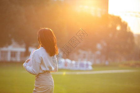 夕阳下的草地夕阳下的女大学生背景
