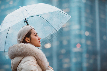 冬季女性户外下雨天撑伞看远方图片