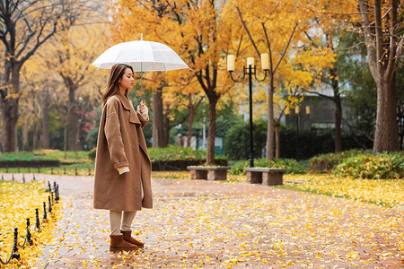 秋季雨天美女撑伞公园散步图片