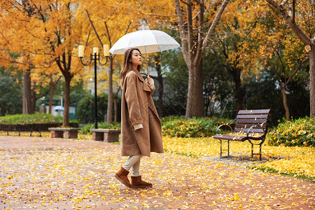 秋季雨天美女撑伞公园散步高清图片