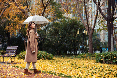 秋季雨天美女撑伞公园散步背景图片