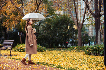 秋季雨天美女撑伞公园散步图片