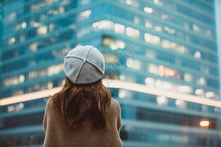迷茫人冬季户外孤单女性背影望向远方商务楼背景