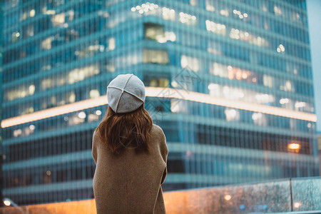 望向一旁冬季户外孤单女性背影望向远方商务楼背景