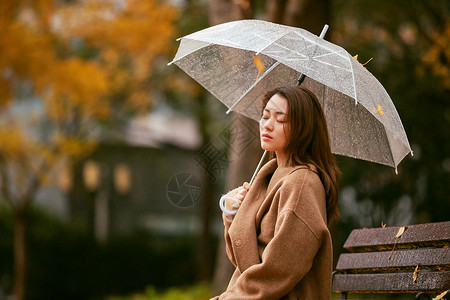 秋季雨天美女银杏落叶撑伞高清图片