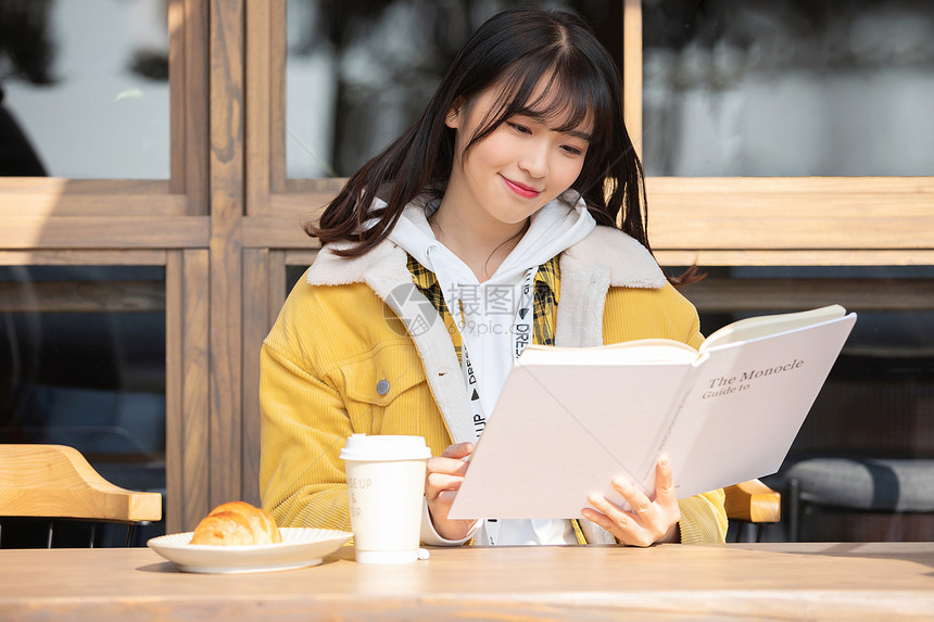 坐在咖啡厅看书的女大学生 图片