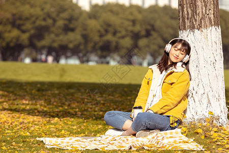 金色耳机素材坐在满地银杏叶下听音乐的女孩背景