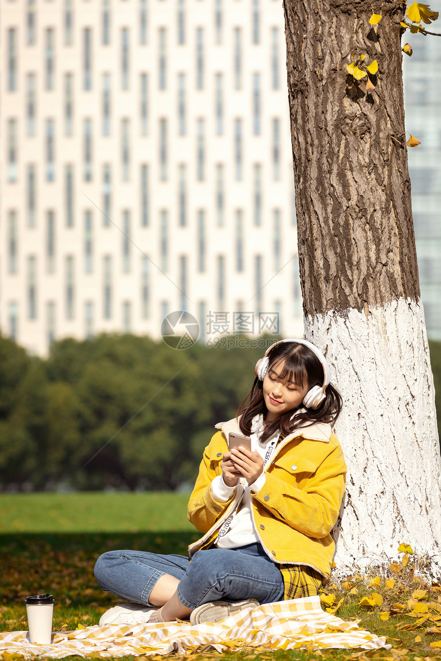 倚靠在银杏树下听音乐的女孩 图片