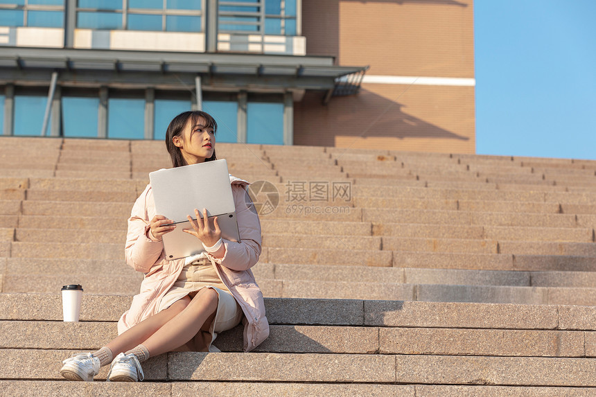 坐在学校台阶上使用电脑的女同学图片