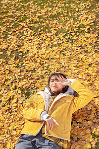 躺在铺满银杏叶草坪上午休的甜美女孩图片