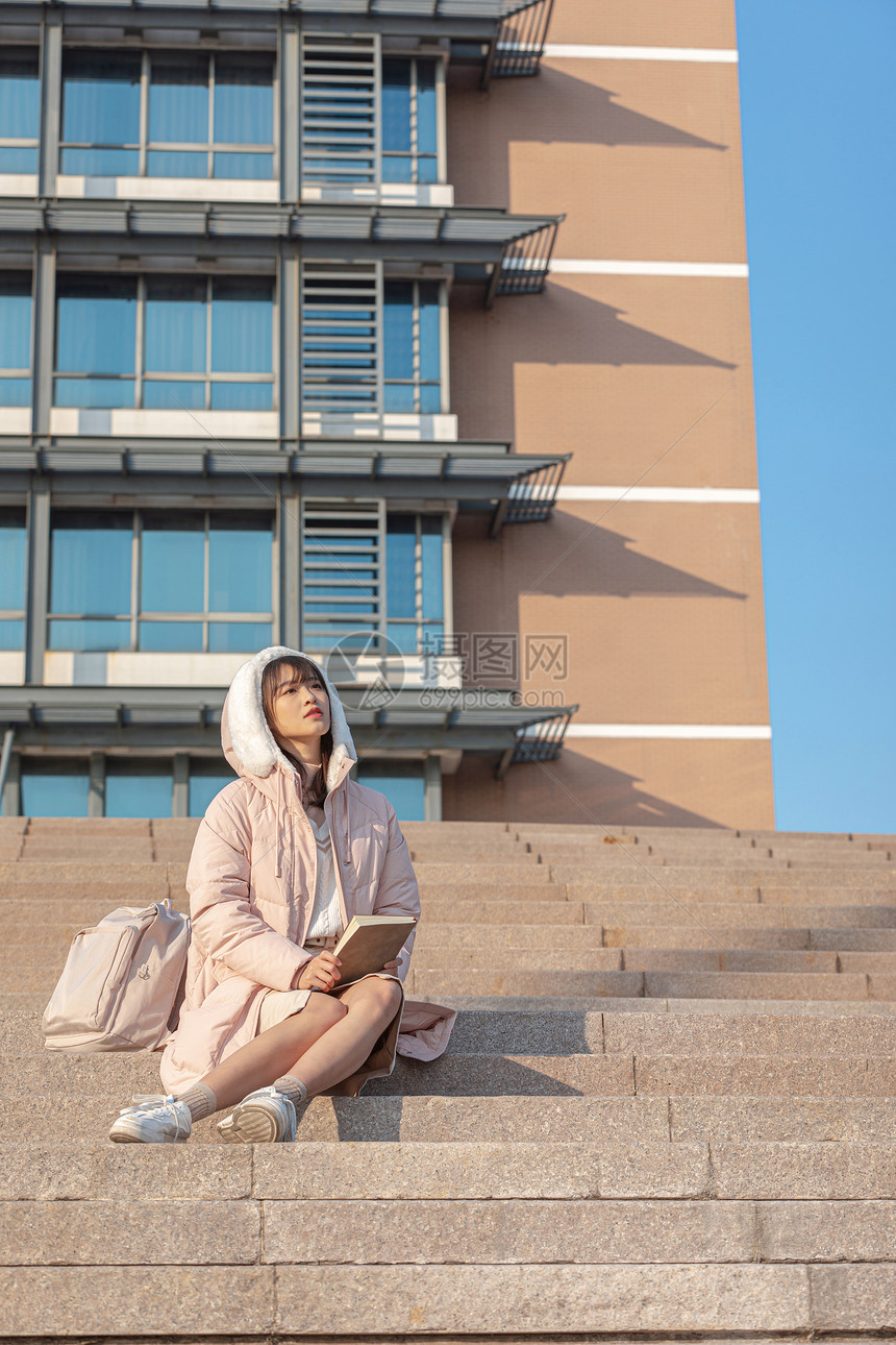 坐在台阶上阅读的女大学生图片