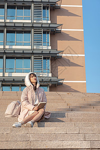 坐在台阶上阅读的女大学生图片