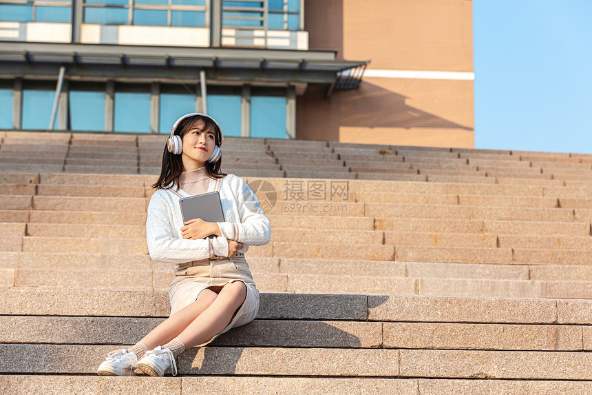 坐在台阶上听音乐的甜美女孩图片