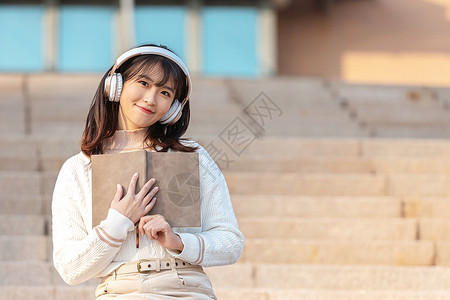 戴耳机女孩坐在台阶上听音乐的甜美女孩背景