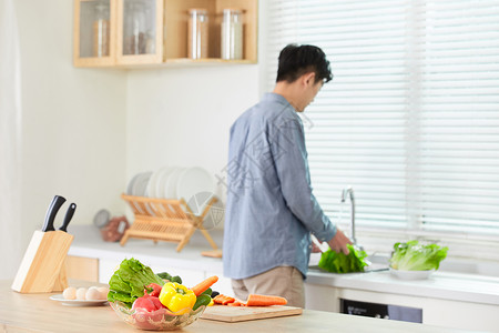 年轻男士在厨房洗菜背影背景图片