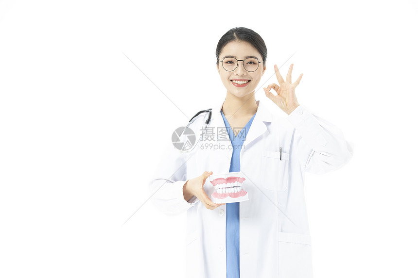 女性牙医拿着假牙ok手势图片