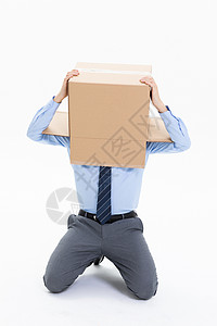 跪在地上头上套纸盒箱的绝望商务男性图片