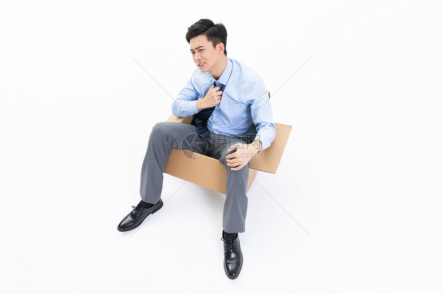 烦躁崩溃的男性青年坐在纸盒箱里图片