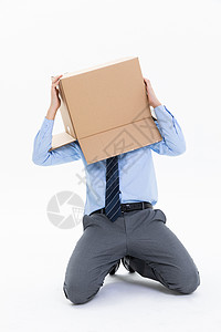 跪在地上的青年男性头上套着纸盒箱图片