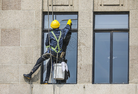 高空作业建筑工人正在清洗大楼外立面的高空清洗工劳动人民背景