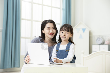妈妈陪着女儿用笔记本电脑上网课高清图片
