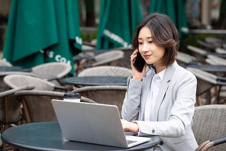 商务职业女性在户外看着电脑打电话图片