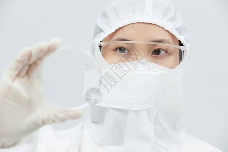 医生细胞穿防护服的科研人员查看细胞培养皿背景
