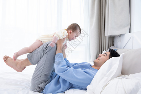 爸爸和婴儿在床上玩耍图片