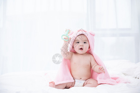 粉色婴儿婴儿在床上拿着玩具玩耍背景