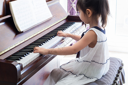 弹钢琴的小女孩小女孩练习弹钢琴背景